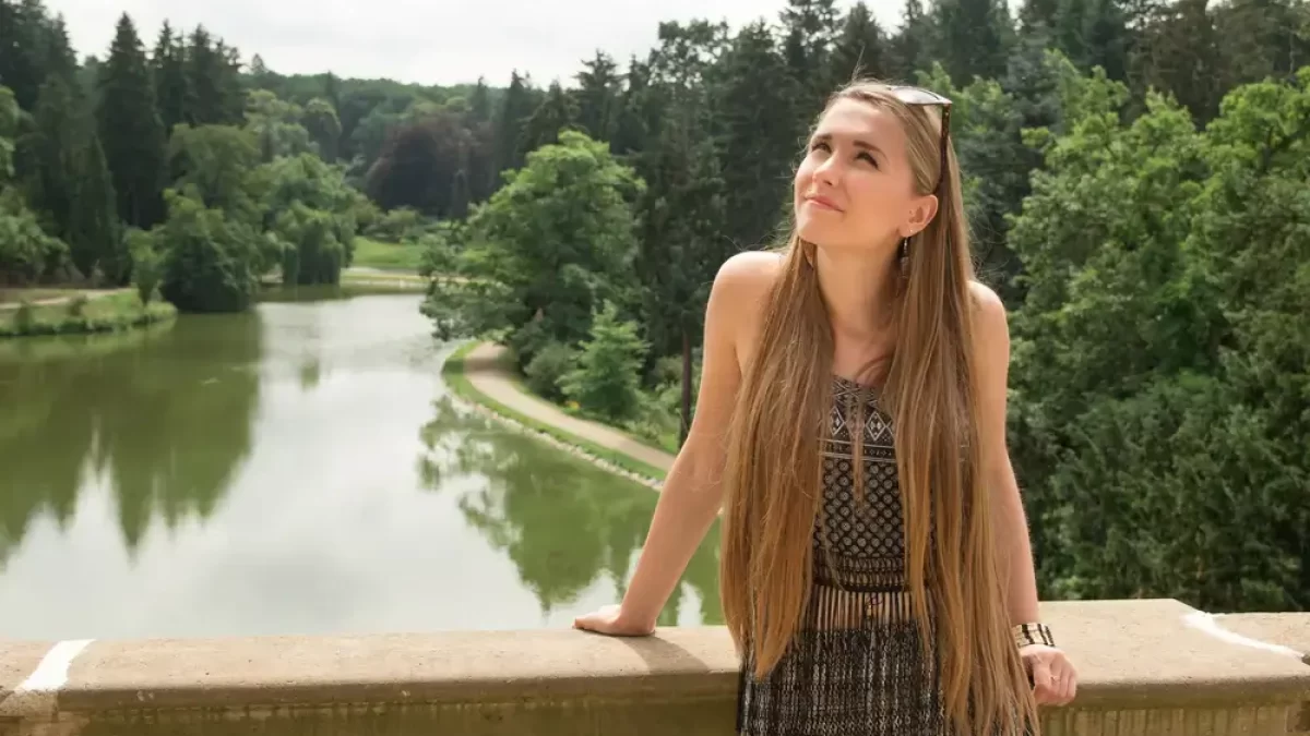 Mladá žena stojí na mostě v zámeckém parku Průhonice.