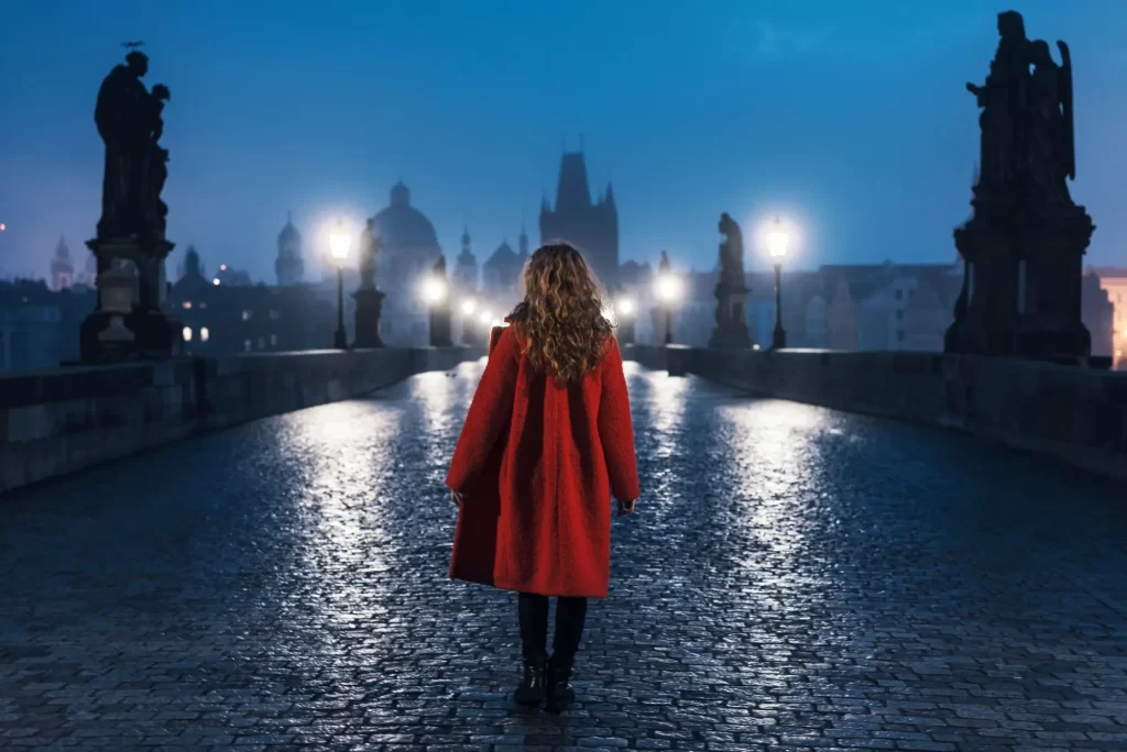 Žena kráčící tajemnou noční Prahou. 