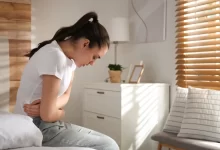 žena v bolestech se drží za břicho