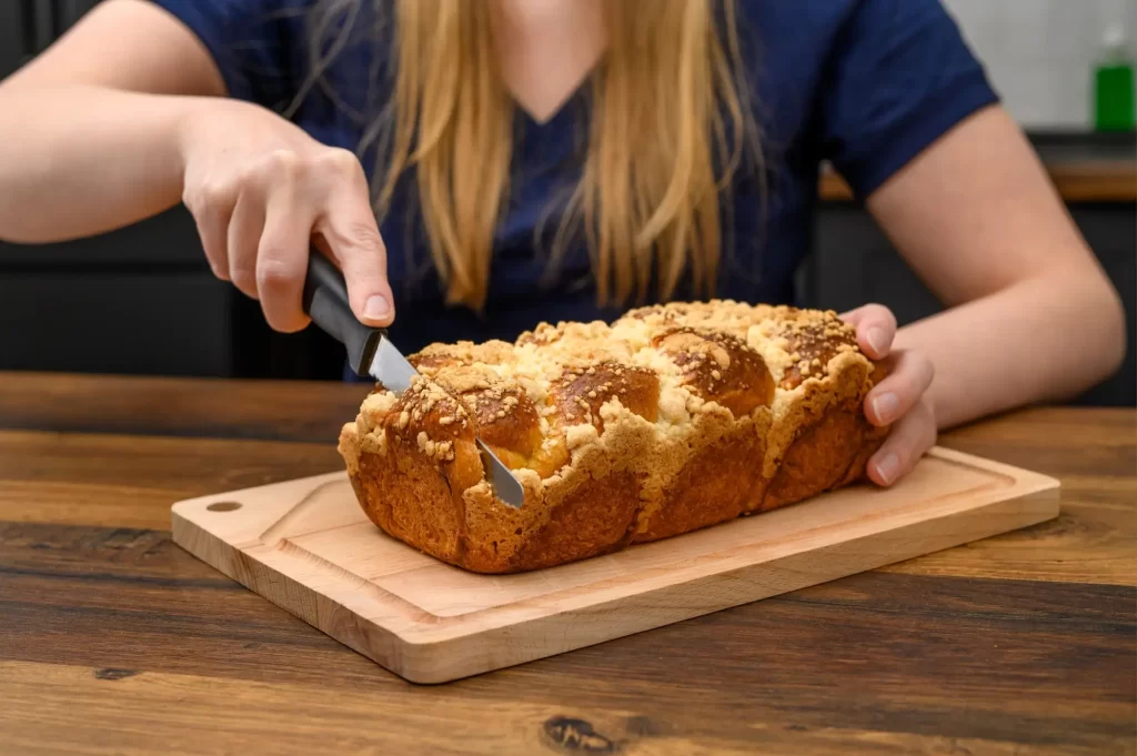 Žena krájející pečený challah s drobenkou