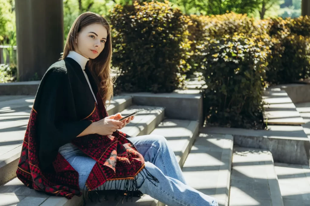 žena v peleríně sedí na schodech