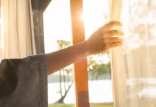 žena pokládá ruku na záclony na okně