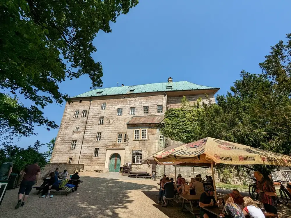 shutterstock_2317812749 (1) - SportDeník Hrad Houska. Pod ním je stánek s mnoha turisty.