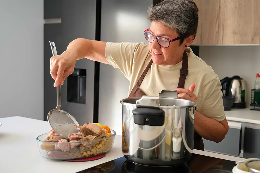 žena vyndavá maso z papiňáku