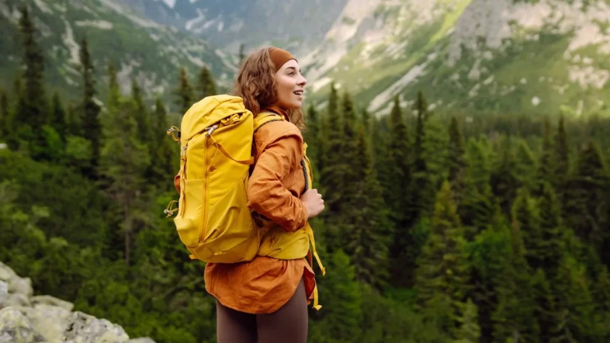 Žena s batohem na turistické cestě v horách.