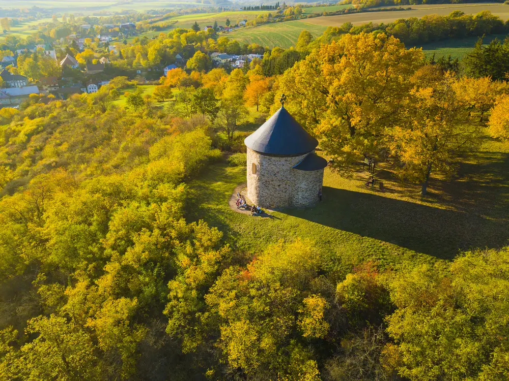 shutterstock_735425662 - SportDeník Rotunda svatého Petra a Pavla nedaleko Starého Plzence. Na lavičce vedle ní sedí turisté.