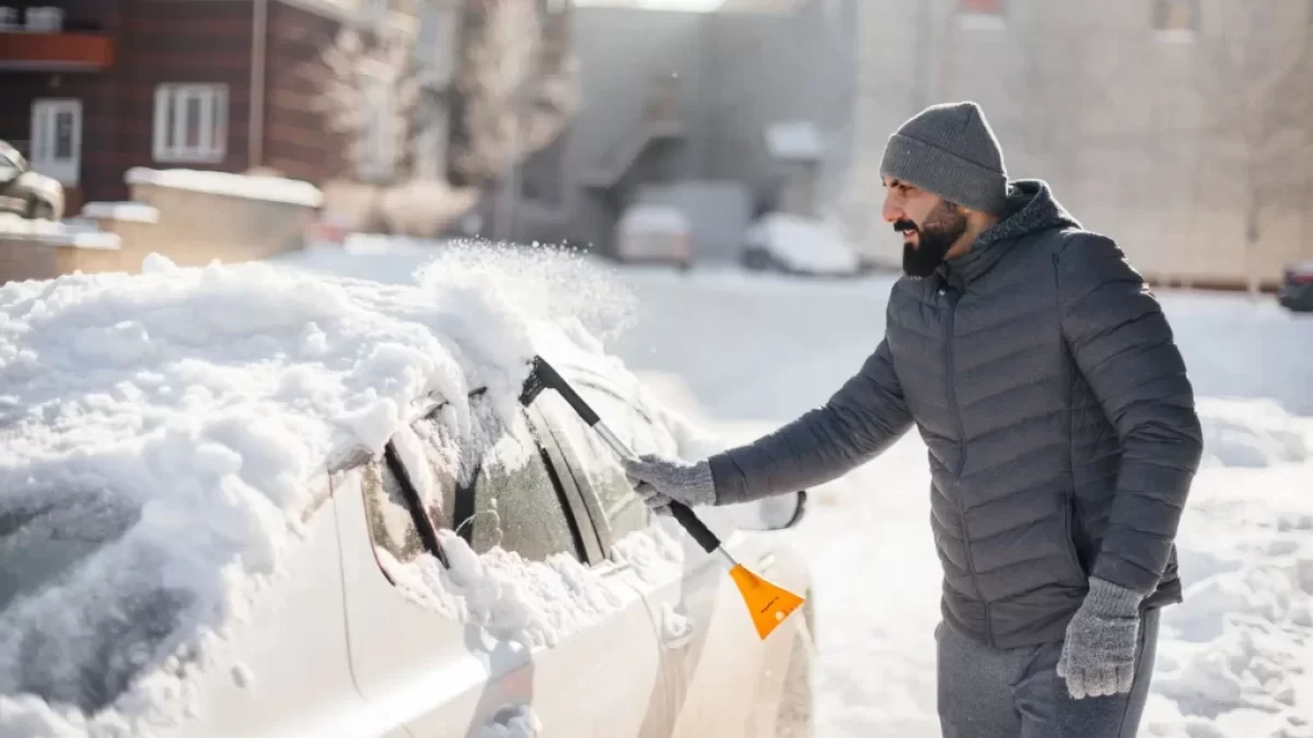 muž ometá auto od sněhu