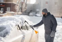 muž ometá auto od sněhu