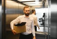 Muž stojí s krabicí ve výtahu