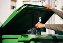 Muž vyhazuje pytel s odpadky do popelnice