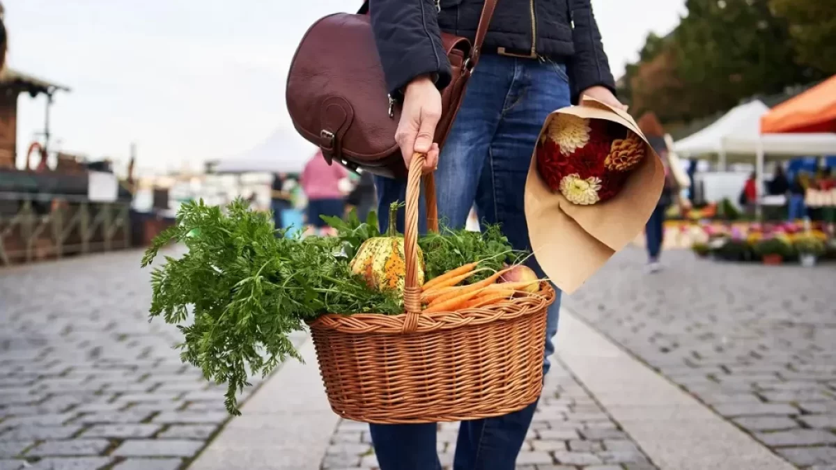 Mladá žena držící košík s farmářskými produkty