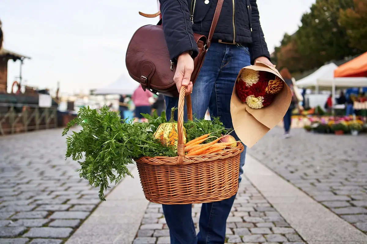 Mladá žena držící košík s farmářskými produkty