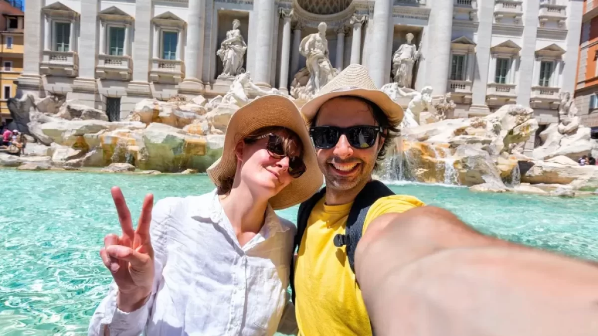 Mladý rozesmátý pár si dělá selfie před slavnou Fontánou di Trevi v Římě