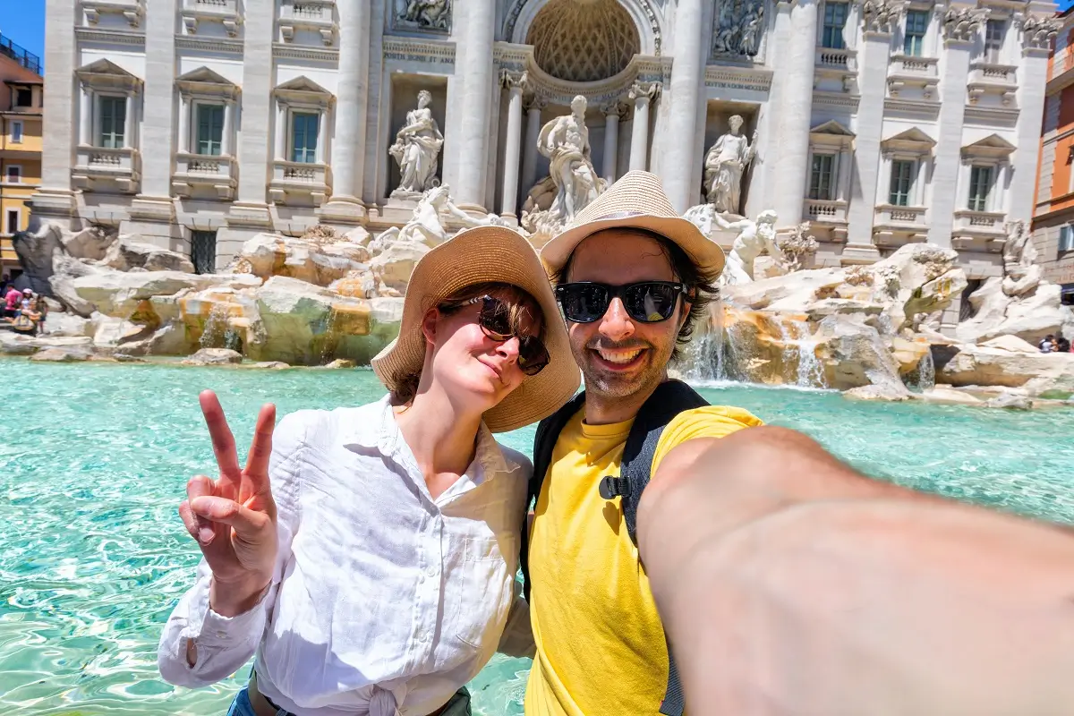 Mladý rozesmátý pár si dělá selfie před slavnou Fontánou di Trevi v Římě