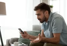 muž drží v ruce telefon