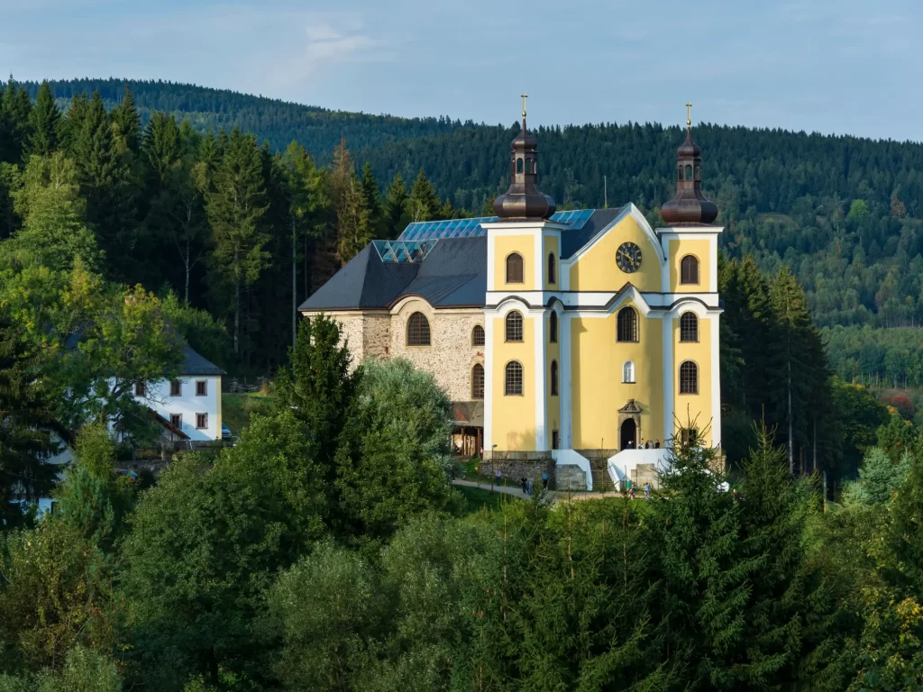 Kostel na kopci obklopený lesem