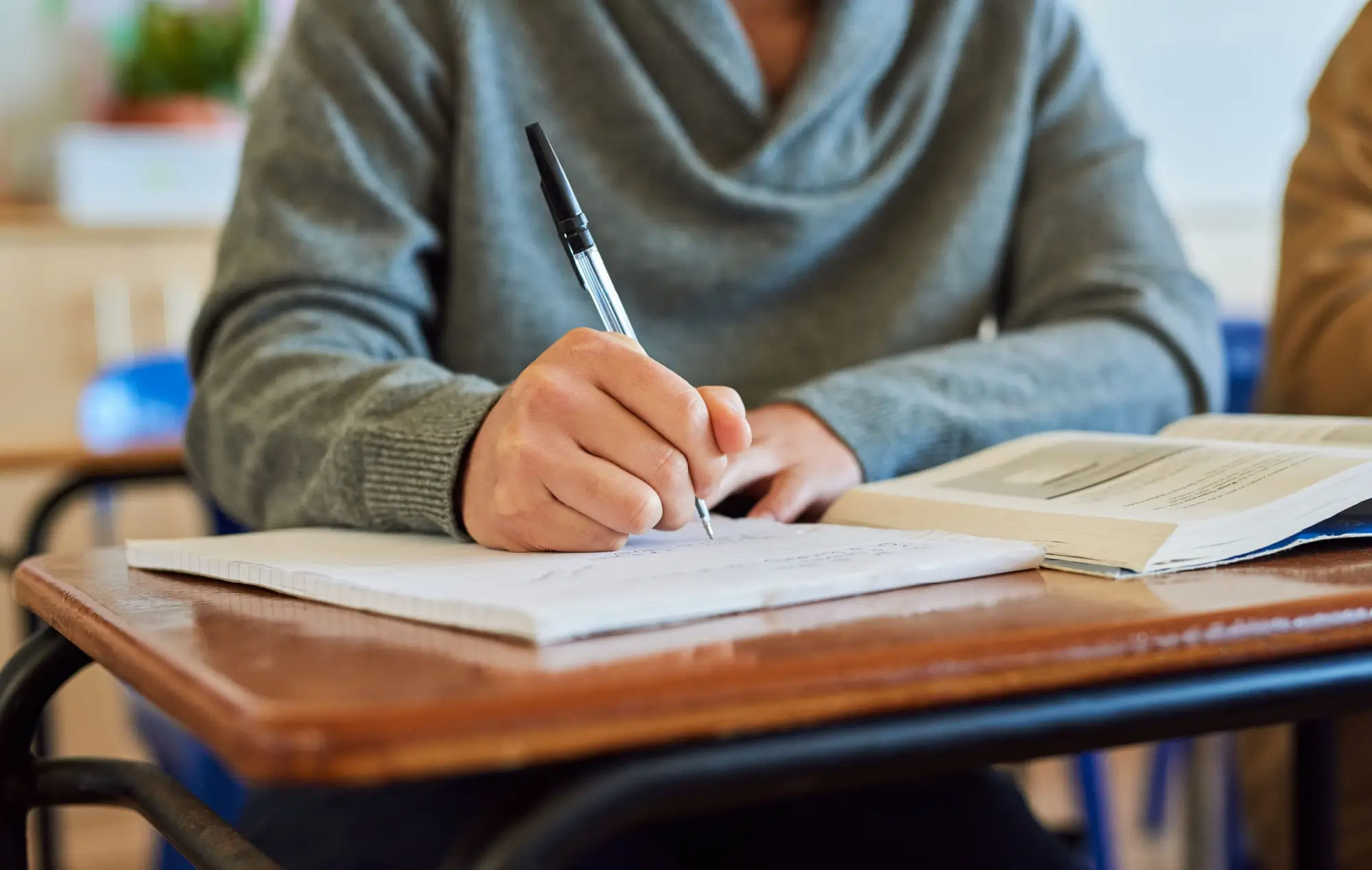 Student zapisující si poznámky do sešitu