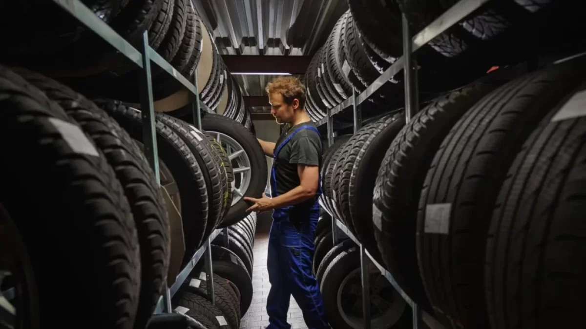 Automechanik mezi regály s pneumatikami