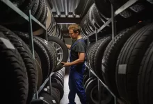 Automechanik mezi regály s pneumatikami