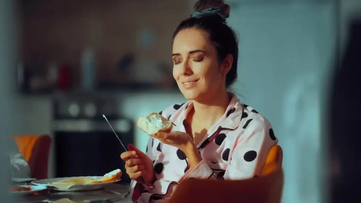 Mladá žena přivírá slastně oči nad chlebem s taveným sýrem