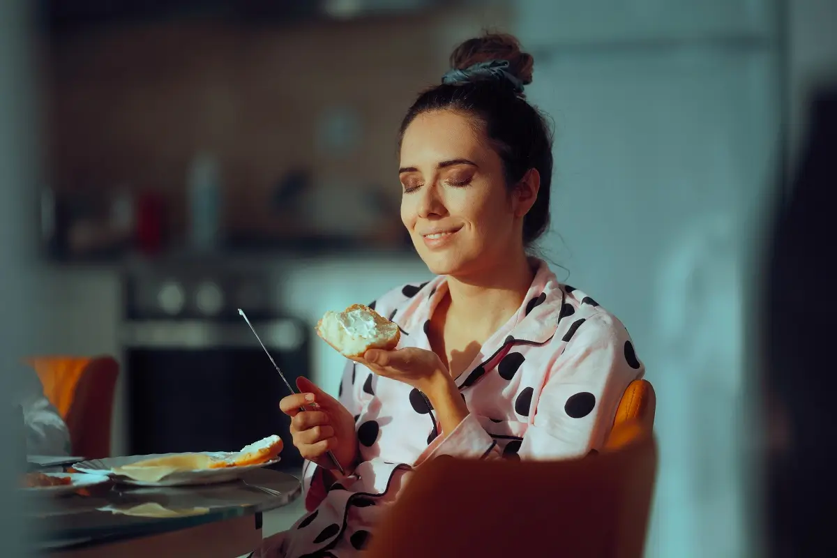 Mladá žena přivírá slastně oči nad chlebem s taveným sýrem