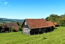 Typická venkovská chalupa v Bílých Karpatech, malý domek s červenou střechou, dřevěnými stěnami a výhledem na krajinu