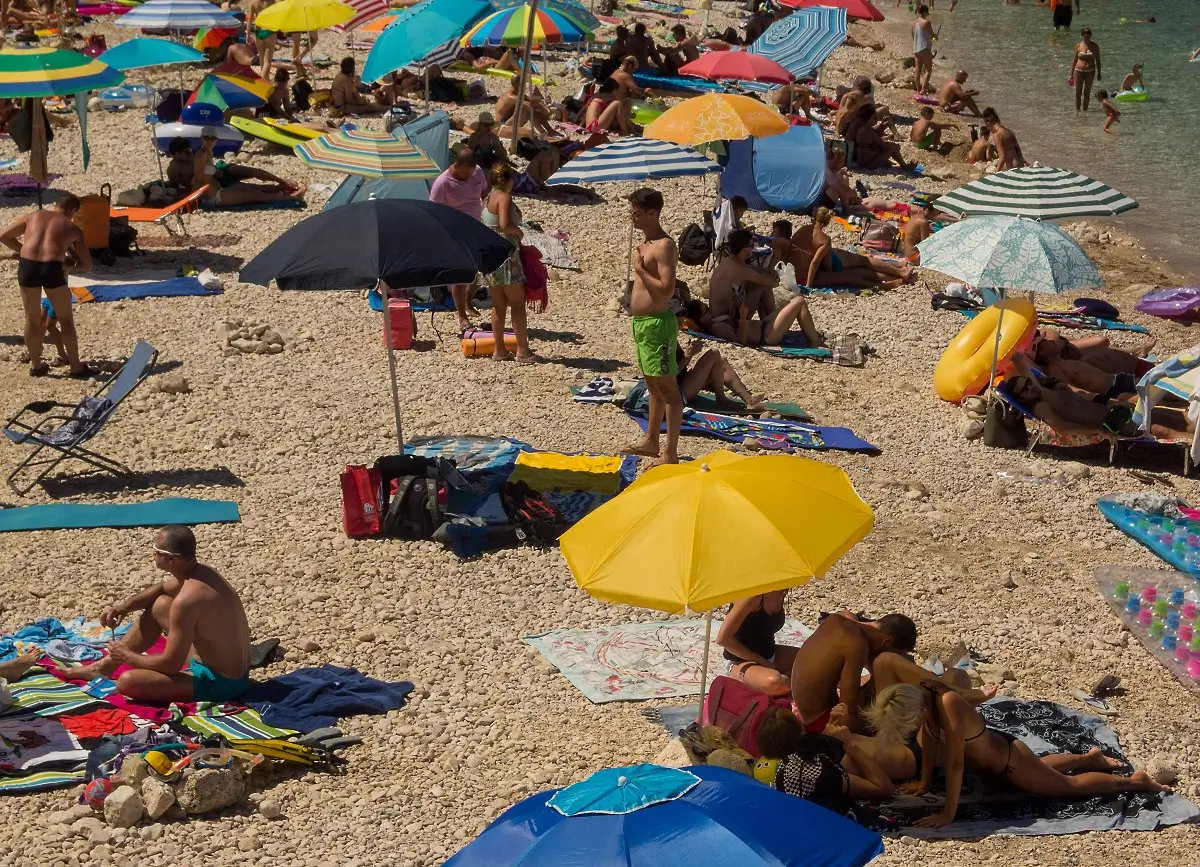 Pláž u moře plná slunečníků a slunících se turistů