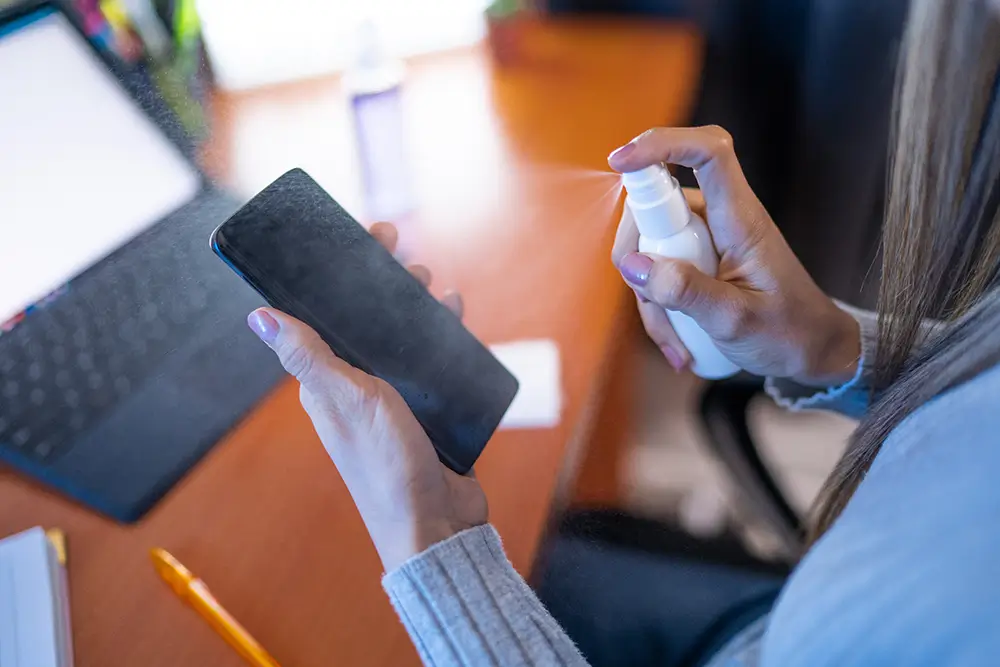 Sprej nestříkejte přímo na displej, ale na hadřík. - SportDeník žena stříká sprej na telefon