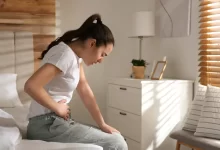 žena sedící na posteli se zdravotními problémy
