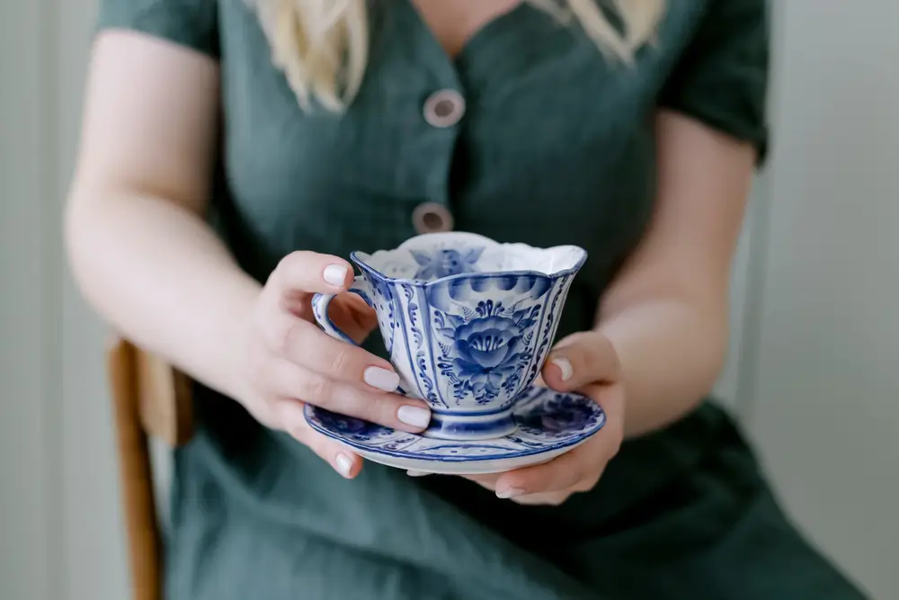 žena držící porcelánový šálek