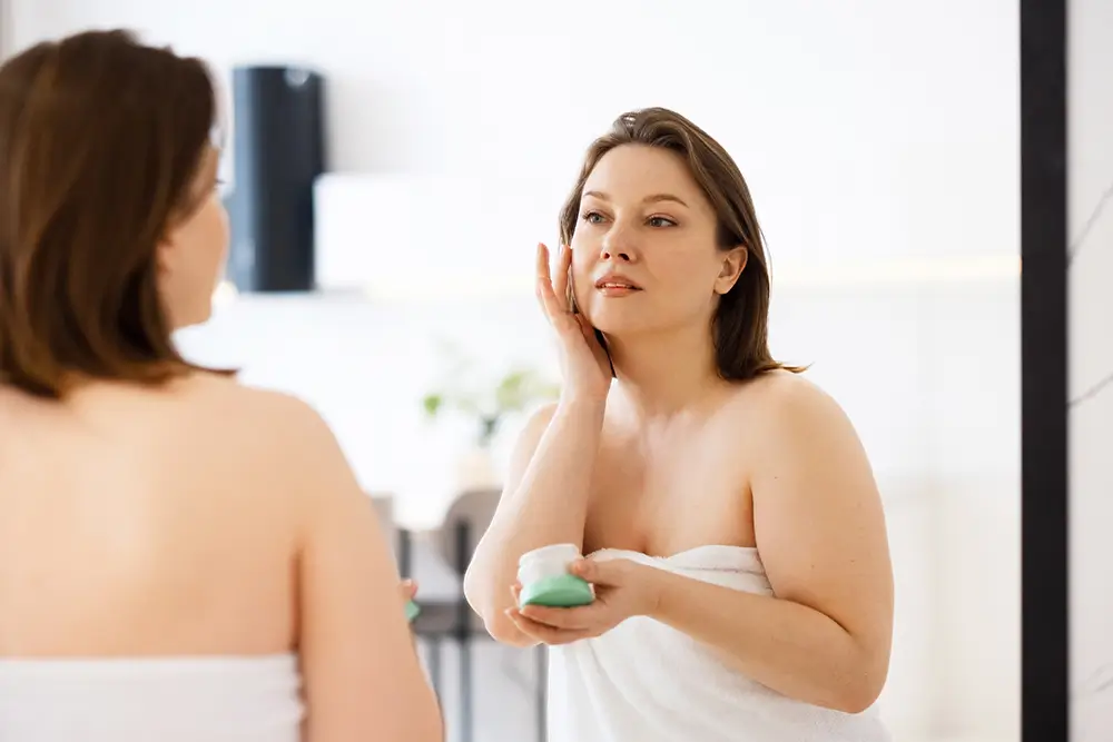 Retinol vyhlazuje jemné vrásky, dovede zmenšit viditelnost pórů i stařeckých skvrn. - SportDeník žena aplikuje na pleť krém před zrcadlem