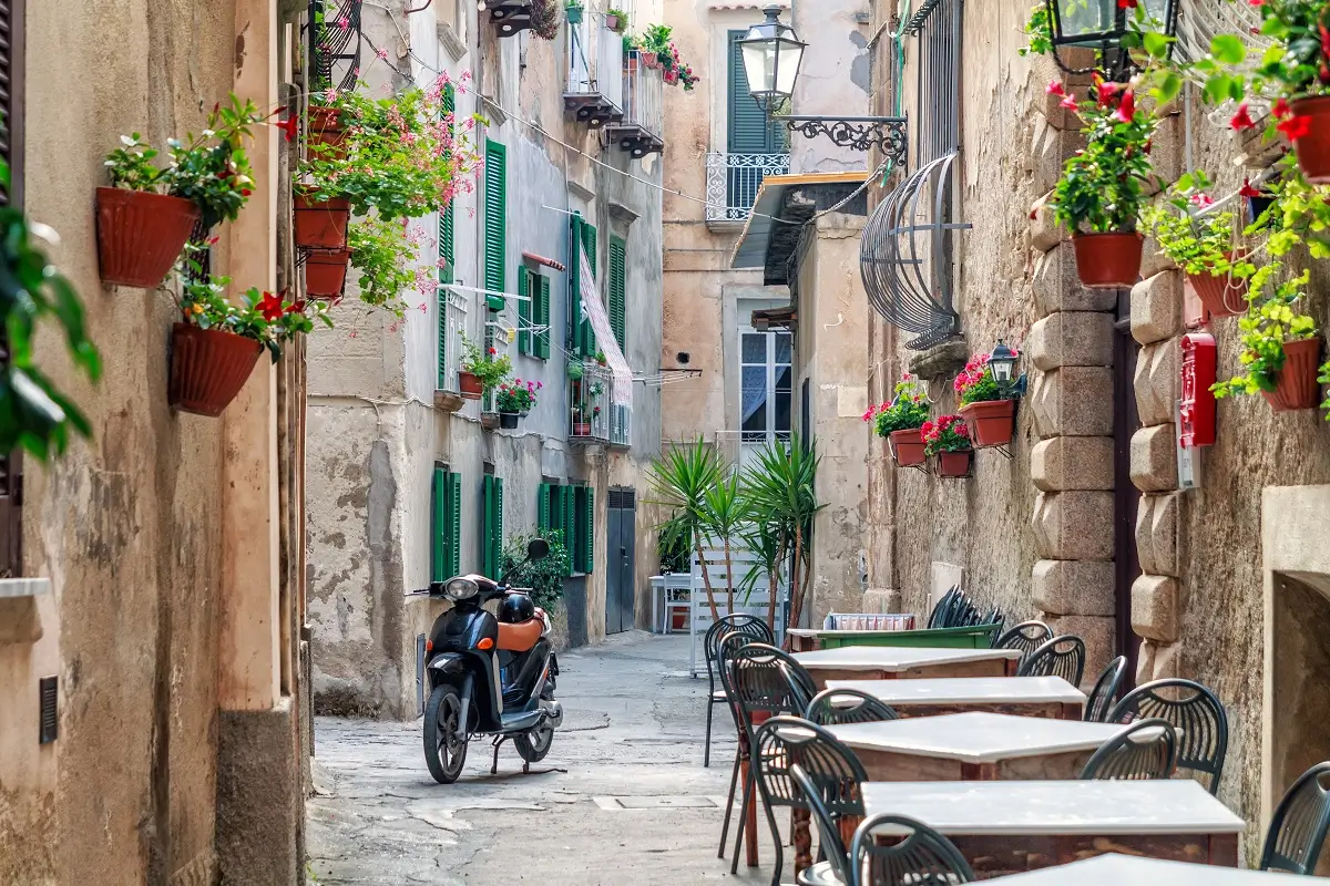 Malebná starobylá ulička v italské Kalábrii se stoly a motorkou