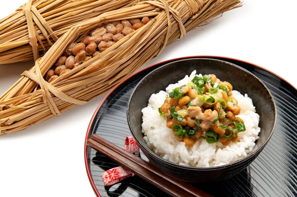 Natto 1 - SportDeník Miska rýže, na které je na hromádce pokrm z fermentovaných sójových bobů.