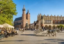 Pohled na centrum polského města Krakov s typickým kočárem taženým koňmi a plnou zahrádkou před jednou z restaurací