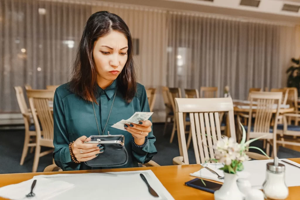 Shutterstock_1026774601 - SportDeník Žena sedící v restauraci a počítající peníze