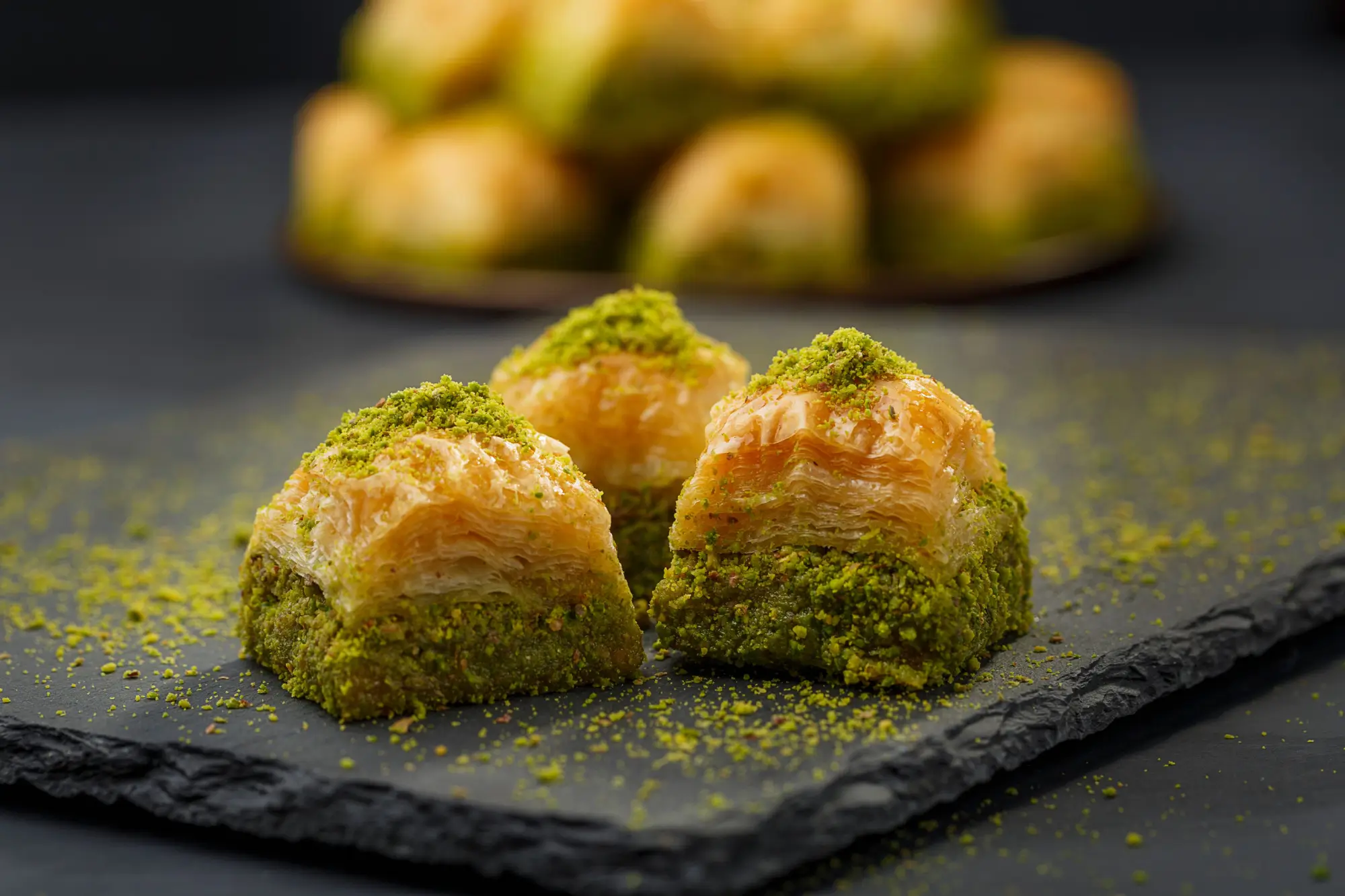 Tři kousky baklavy na černém tácu
