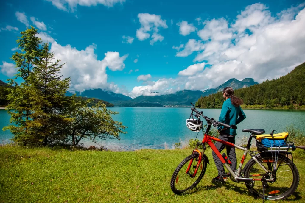 Shutterstock_2029590578 - SportDeník Cyklista stojící s kolem na břehu alpského jezera