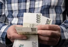 Starší muž držící v ruce dvoutisícovky