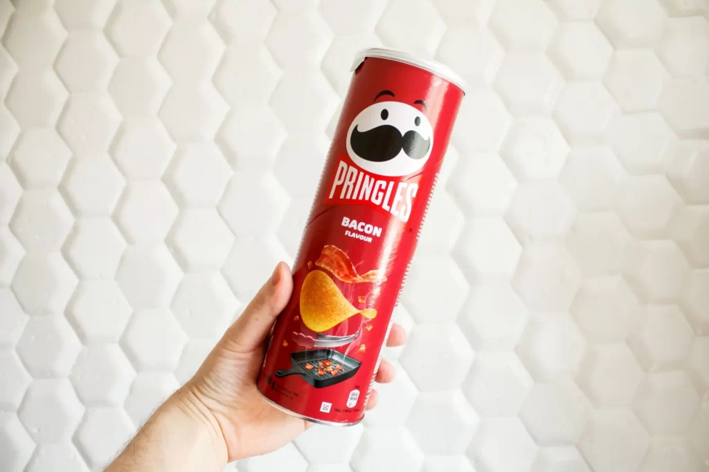 Ruka držící balení slaninových Pringles
