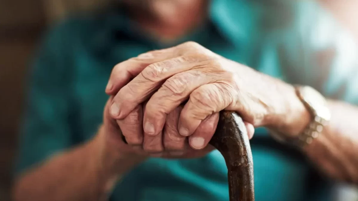 Ruce seniorky svírající chodeckou hůl