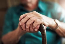 Ruce seniorky svírající chodeckou hůl