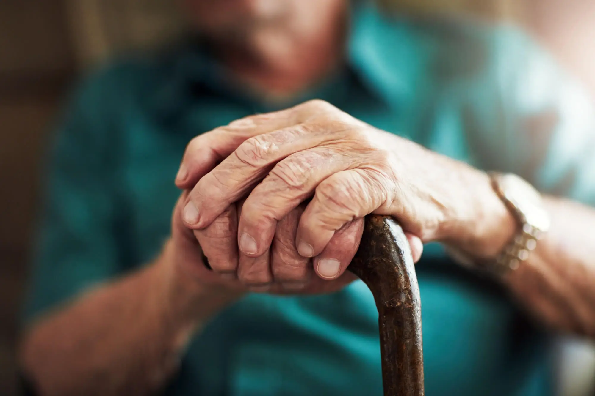 Ruce seniorky svírající chodeckou hůl