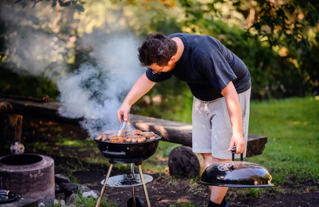 Shutterstock_2469447541 - SportDeník Muž grilující maso na přenosném grilu