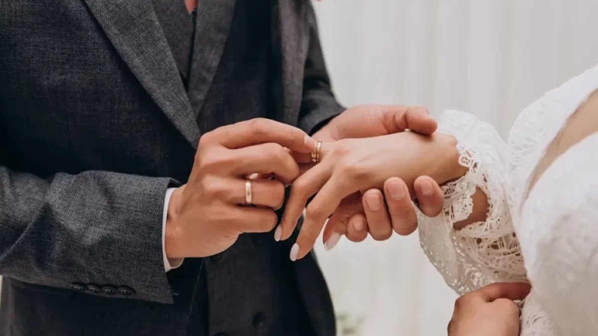 Mužská ruka navlékající prsten na ženskou ruku