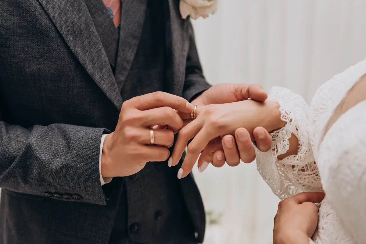 Mužská ruka navlékající prsten na ženskou ruku