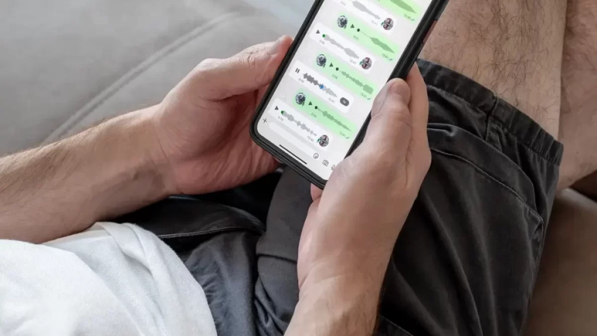 Muž drží v ruce telefon se zprávami v aplikaci WhatsApp