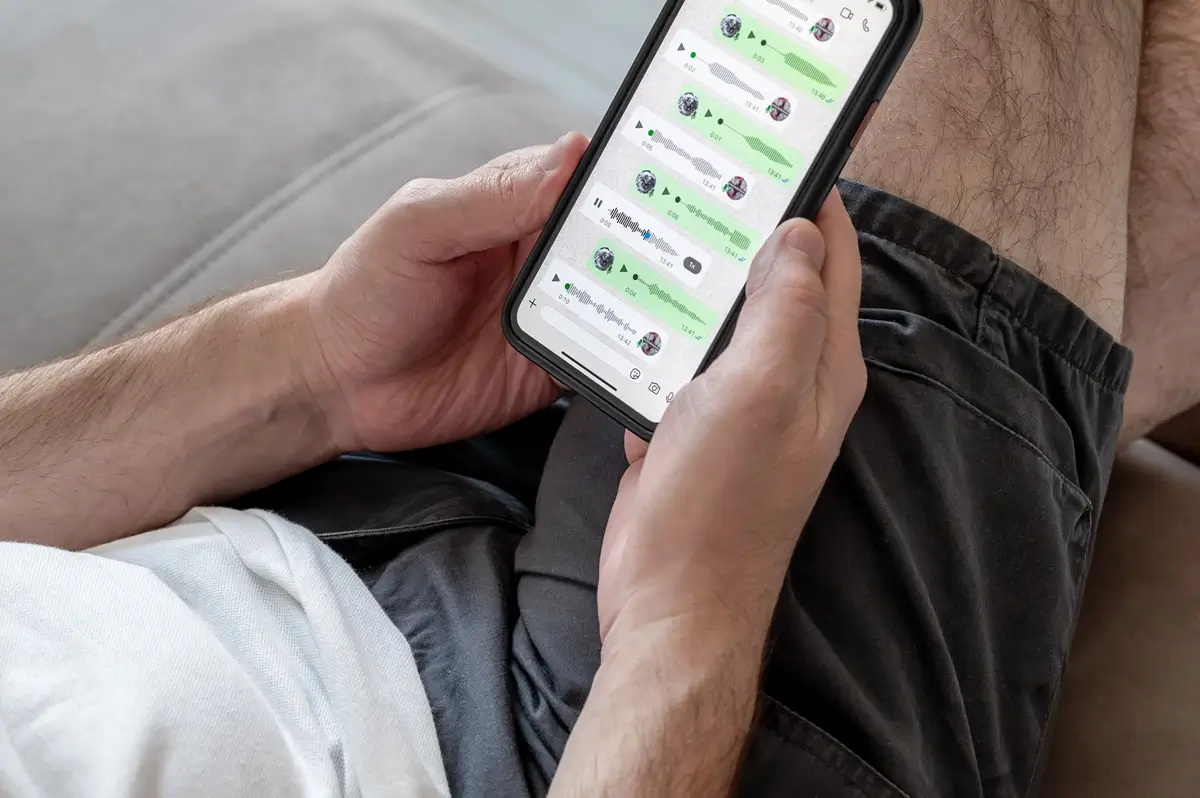 Muž drží v ruce telefon se zprávami v aplikaci WhatsApp