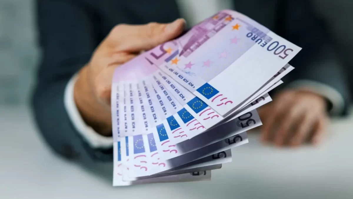 Muž podávající velký balík euro bankovek