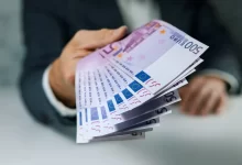 Muž podávající velký balík euro bankovek