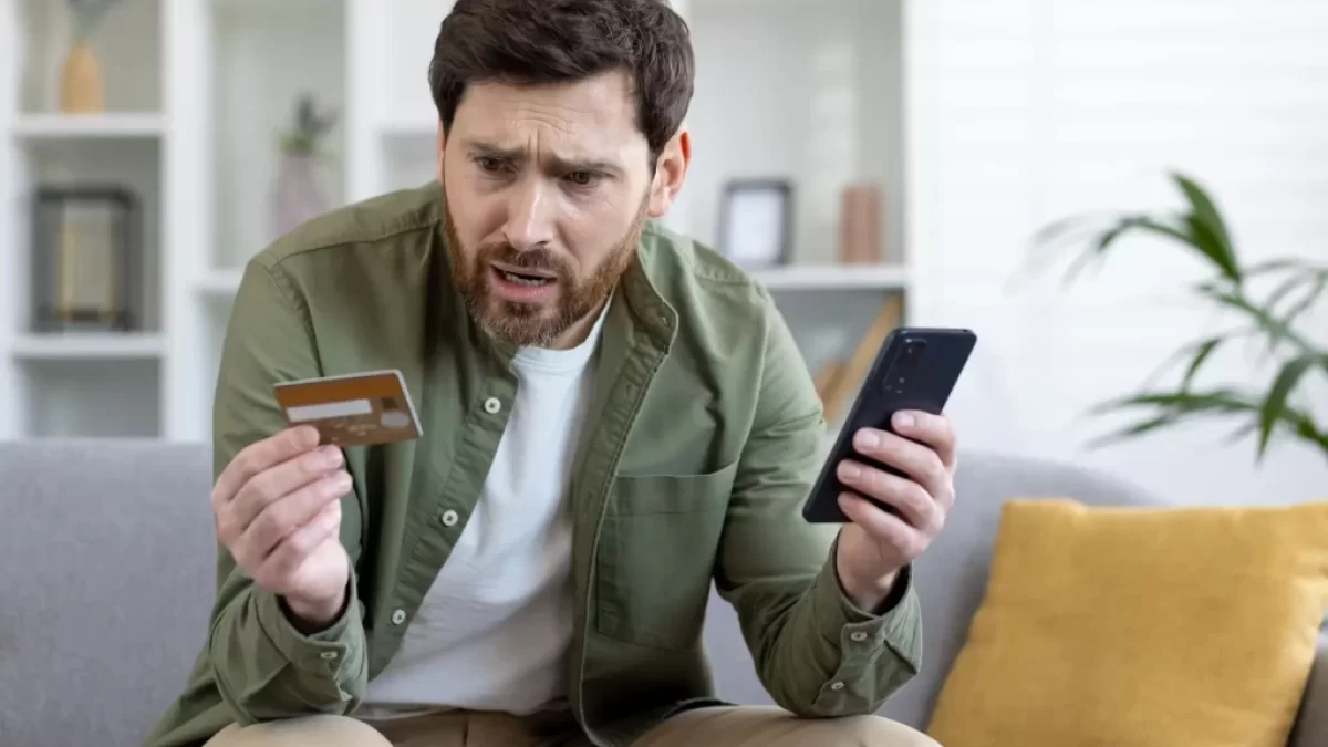 Nešťastný muž s kreditní kartou a mobilem
